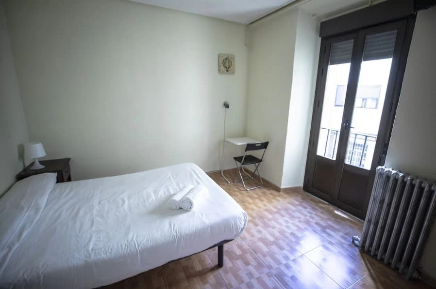 Room with a double bed, desk and a balcony over the street