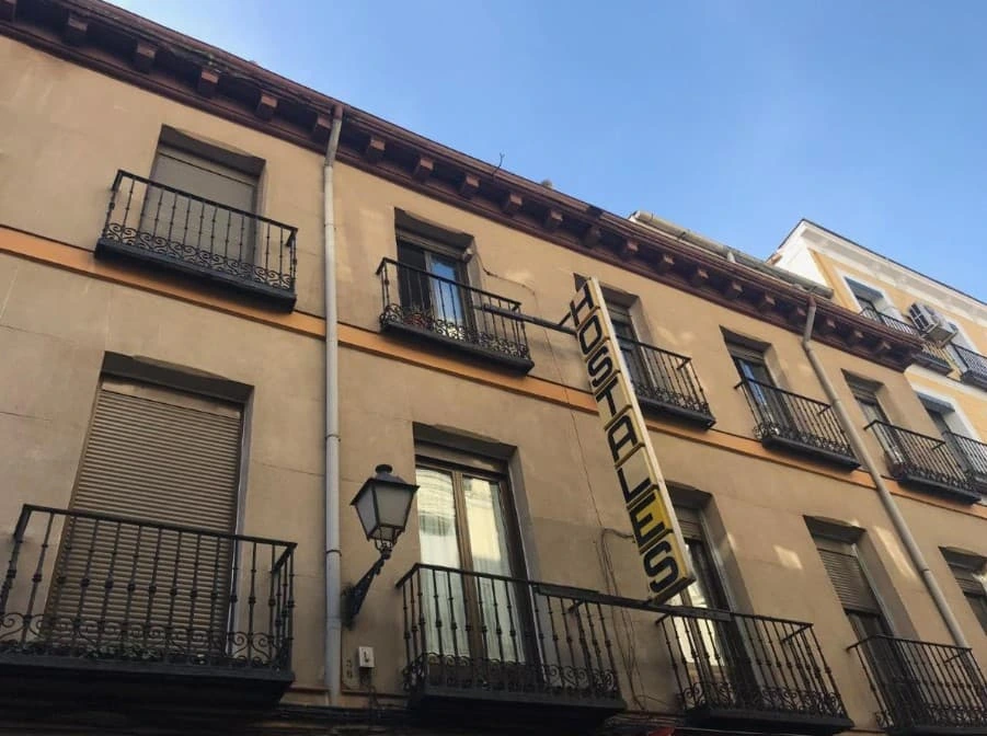 Building of Hostal Los Perales Madrid with wrought-iron balconies and the vertical sign