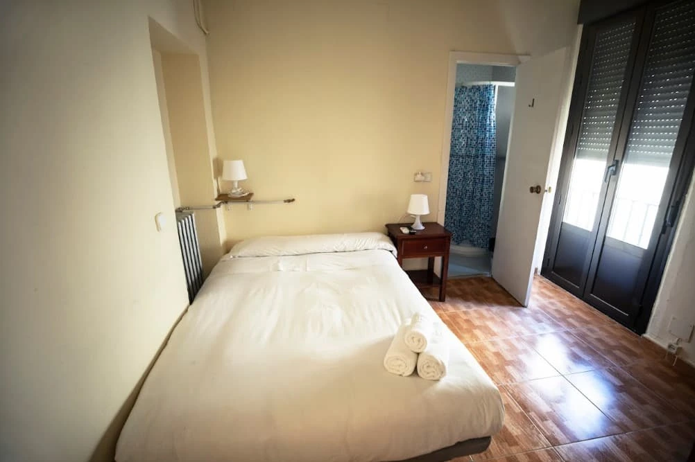 Double room with the bathroom at the back and a balcony door